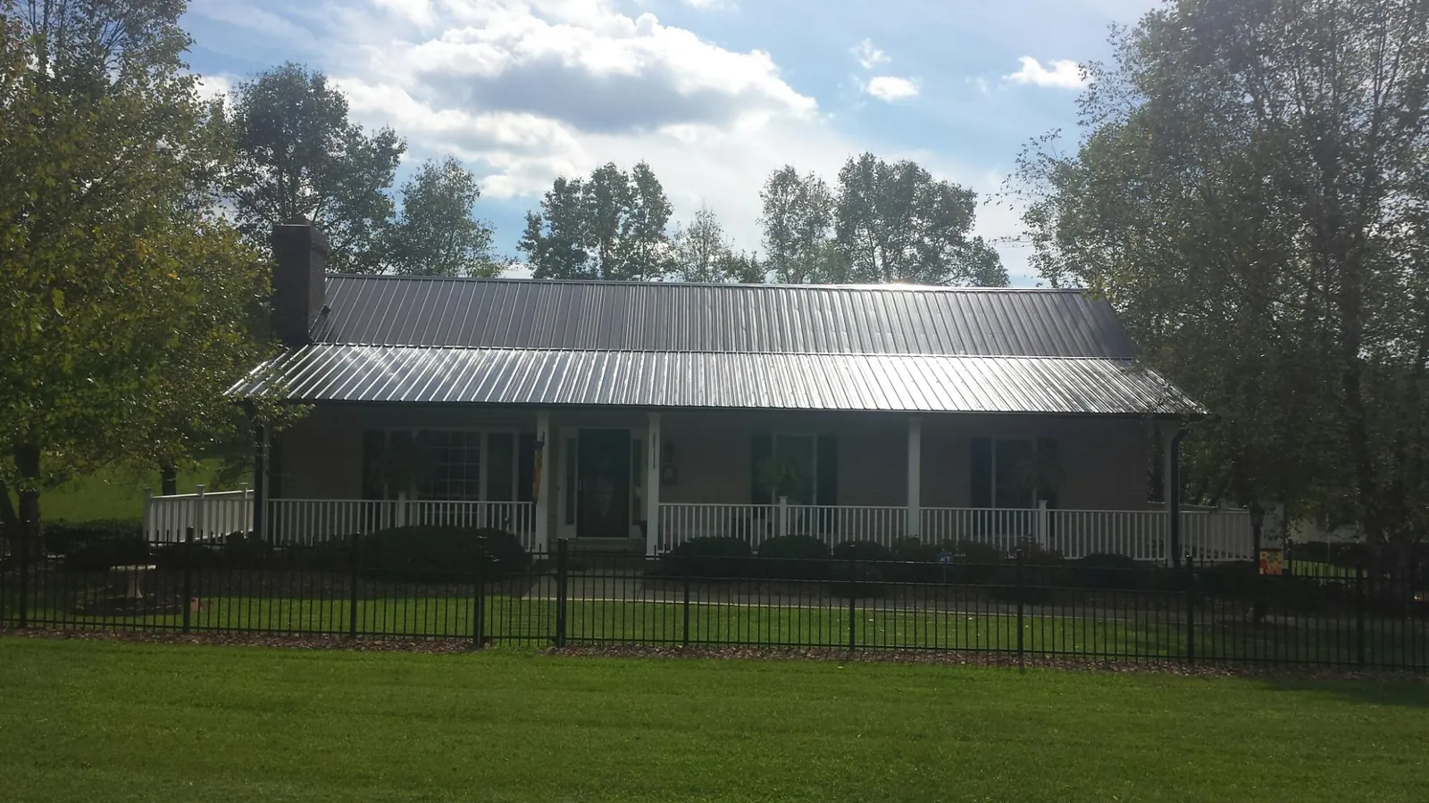 Gray metal roof on a brick ranch with a full width front porch — Gutter Guard Installation work by our crew in Jonesboro