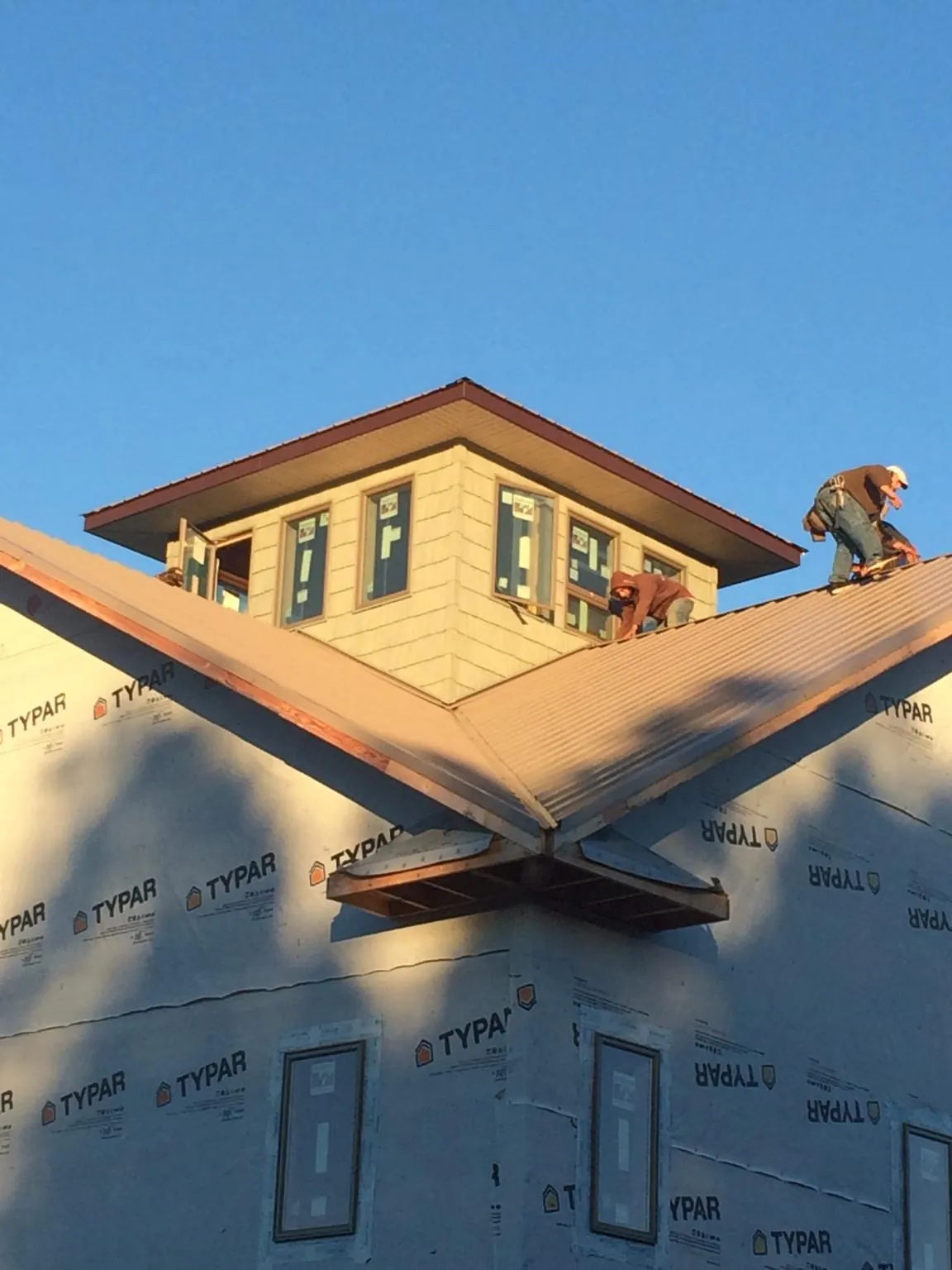 Roofers working around a rooftop cupola on a new metal roof at sunset — Roof Waterproofing in Jonesboro by Roofing Brothers